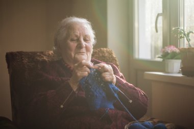 Yaşlı kadın evde oturur ve konfeksiyon dokuma kumaşlar