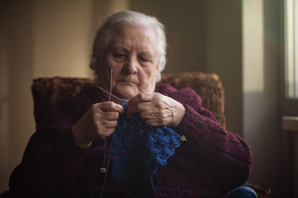 The old woman sits at home and knits garments