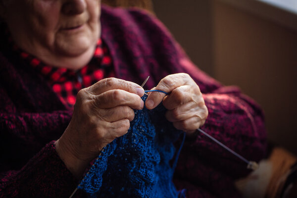 The old woman sits at home and knits garments