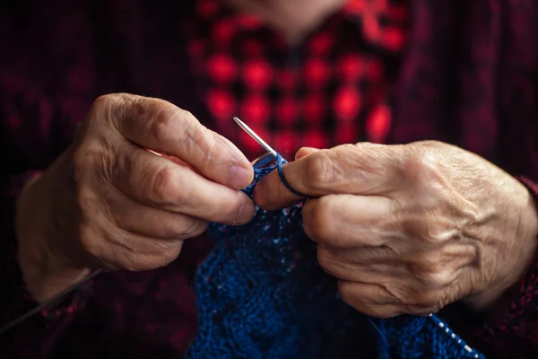 De oude vrouw zit thuis en breit kleding. — Stockfoto