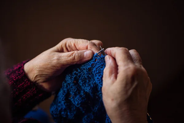 Yaşlı kadın evde oturur ve konfeksiyon dokuma kumaşlar. — Stok fotoğraf