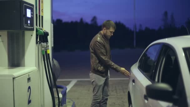 Estación de llenado. Un hombre llena su auto con gasolina por la noche — Vídeo de stock