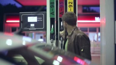 Akaryakıt istasyonu. Bir adamın arabasına benzin ile geceleri doldurur