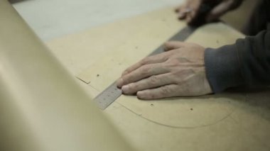 Fabrikada çalışan adam. Çanta yapmak için karton çerçeve keser.