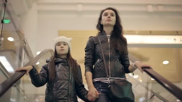 Mor och dotter i en stormarknad på rulltrappan. — Stockvideo