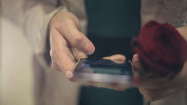 Het meisje met een roos in de hand gebruik een telefoon meisje schrijft haar vriendje bericht. — Stockvideo
