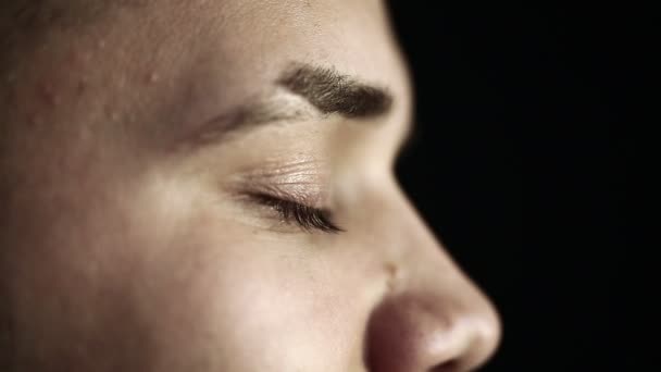 Nahaufnahme Profil Gesicht eines jungen Mannes mit grünen Augen schwarzen Hintergrund. — Stockvideo