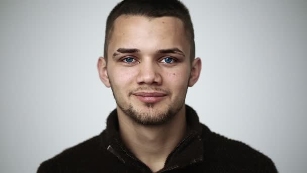 En ung man med blå ögon ler och visar hängslen på tänderna och blinka — Stockvideo
