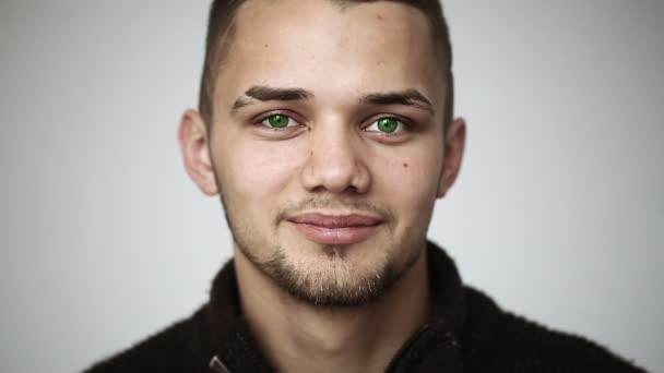 Молодой человек с зелеными глазами улыбается и показывает брекеты на зубах — стоковое видео