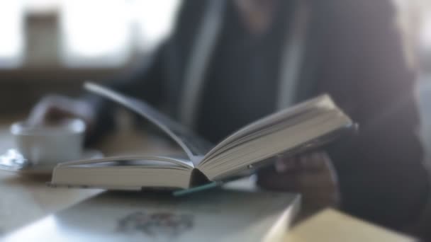 Un hombre en un café bebiendo café y leyendo un libro. Movimiento lento — Vídeos de Stock