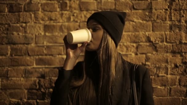 Девочка-подросток на улице ночью пьет кофе и ждет — стоковое видео