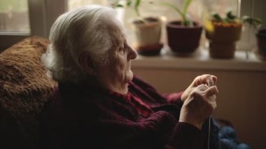 Yaşlı kadın evde oturur ve konfeksiyon dokuma kumaşlar