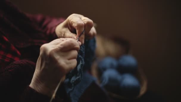 The old woman sits at home and knits garments. — Stock Video