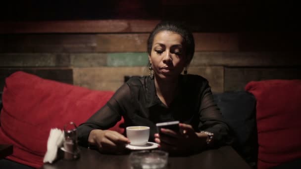 Mulher negra bebendo café quente e usar smartphones — Vídeo de Stock