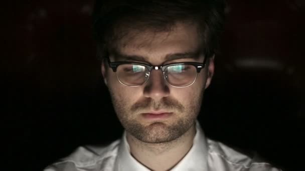 Retrato de un joven con gafas que trabaja de noche. De cerca. — Vídeos de Stock