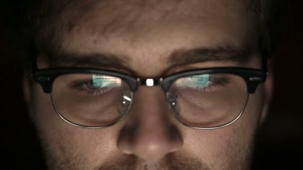 Retrato de un joven con gafas que trabaja de noche. De cerca. — Vídeo de stock