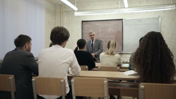 Zeitlupe: Eine Gruppe von Schülern in einem Klassenzimmer, die zuhören, wie ihr Lehrer einen Vortrag hält. — Stockvideo