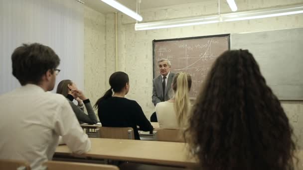 Zeitlupe: Eine Gruppe von Schülern in einem Klassenzimmer, die zuhören, wie ihr Lehrer einen Vortrag hält. — Stockvideo