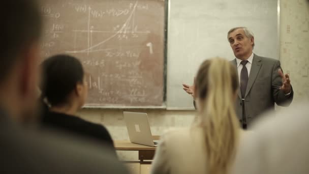 Grupp elever i ett klassrum, lyssnar som deras lärare håller en föreläsning. — Stockvideo