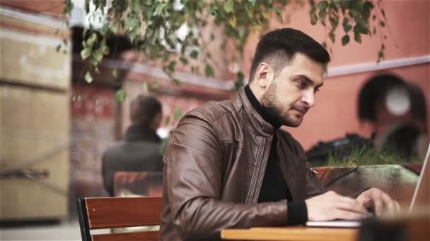 Een man maakt gebruik van een laptop buiten. — Stockvideo