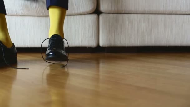 L'homme en chaussettes jaunes porte des chaussures pour attacher des lacets .