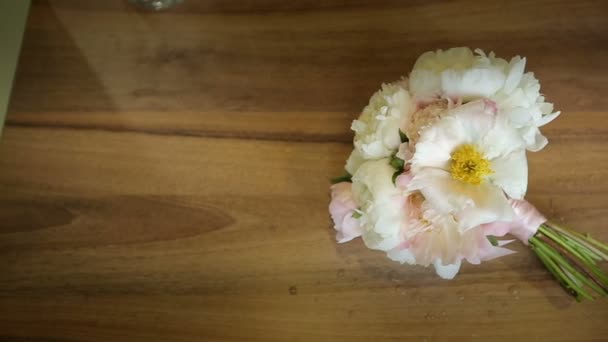 Buquê de flores brancas amarrado com uma fita rosa em uma mesa de madeira. Slider tiro — Vídeo de Stock
