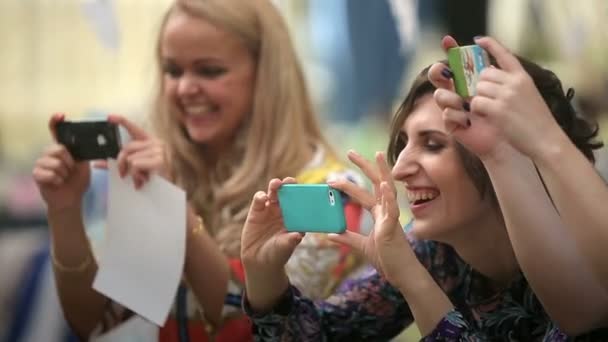 Un grupo de chicas se ríen y hacen fotos en sus iphones — Vídeos de Stock