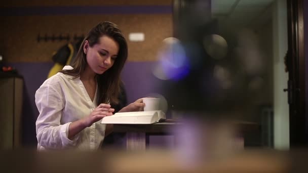 Uma aluna num café a ler um livro. Movimento lento — Vídeo de Stock