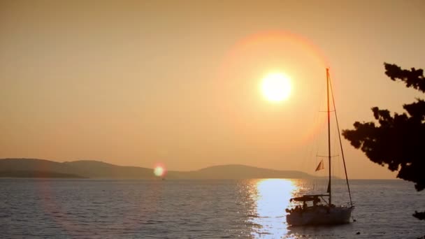 Яхта в морі на заході сонця на тлі гір — стокове відео