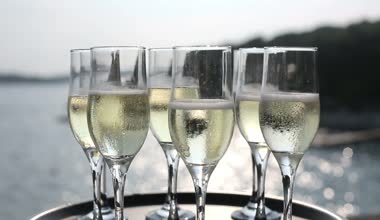 Tepsi şampanya bardakları eller garsona arka planını günbatımı denizde. Yakın çekim