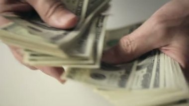 Bir işadamı bir masada sayım yüz dolar faturaları eller. Ağır çekim