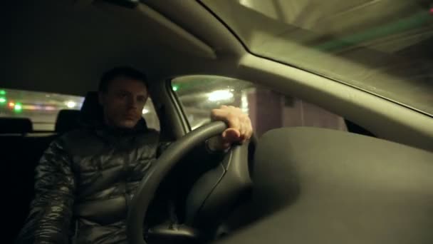 Чоловік водить машину на підземному паркінгу — стокове відео