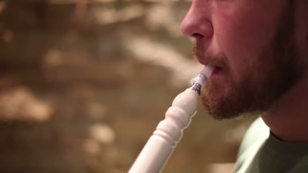 En man med ett skägg röker vattenpipa — Stockvideo