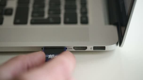 Hand Einfügen der SD-Karte 16GB in den Speicherkartenleser des Laptops — Stockvideo