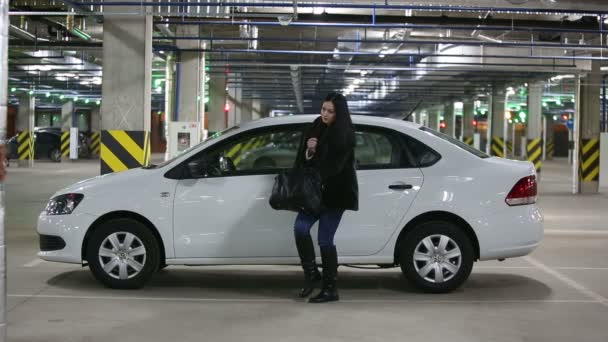 Menina na garagem subterrânea senta-se no carro — Vídeo de Stock
