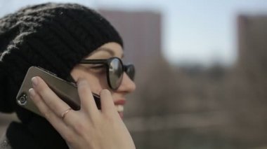 Güneş gözlüklü genç kız telefonla konuşuyor. Ağır çekim