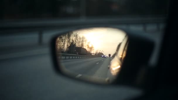 Вид на дорогу в зеркале заднего вида автомобиля на закате — стоковое видео