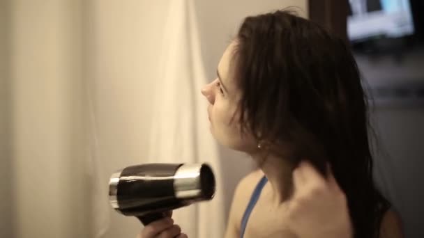 Young woman drying her hair with dryer — Stock Video