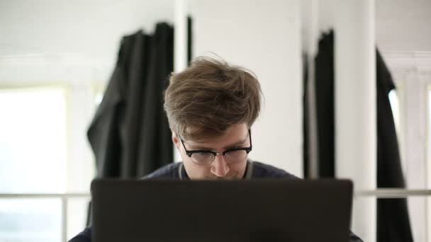 El hombre inteligente con gafas trabaja en la computadora en el estudio — Vídeo de stock