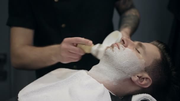 Barber shaves the beard of the client in the barbershop — Stock Video