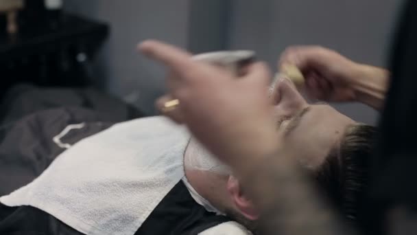 Barber shaves the beard of the client in the barbershop — Stock Video