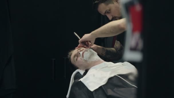Barbeiro barba a barba do cliente na barbearia — Vídeo de Stock