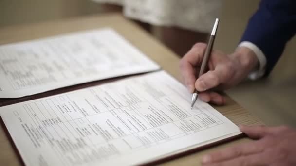La mano del hombre puso una firma en un formulario. Primer plano. Cámara lenta. — Vídeos de Stock