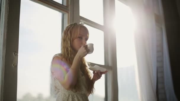 Žena, pití kávy u okna při východu slunce v její útulný domov — Stock video