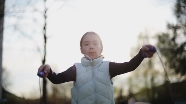 Petite fille sautant corde au coucher du soleil — Video