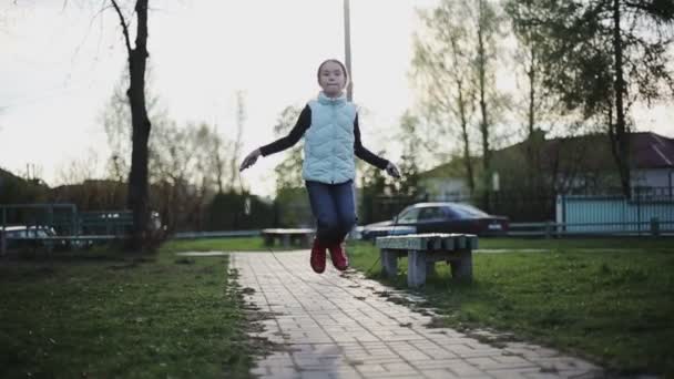 Little girl jumping rope at sunset. Slow motion — Stock Video