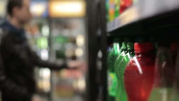 Człowiek w supermarkecie kupując butelkę wody gazowanej. Rozmycie tła — Wideo stockowe