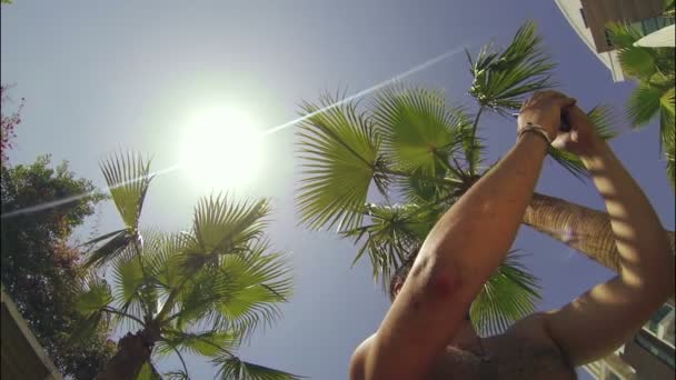 Man fotograferar på telefon ett panorama under palmerna — Stockvideo