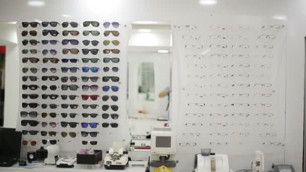 Очки показаны на стене в оптическом магазине — стоковое видео
