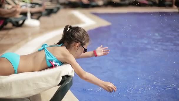 Дитина бризкає воду в басейні в курортному готелі — стокове відео